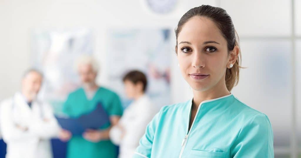 Nurse portrait with medical staff in background