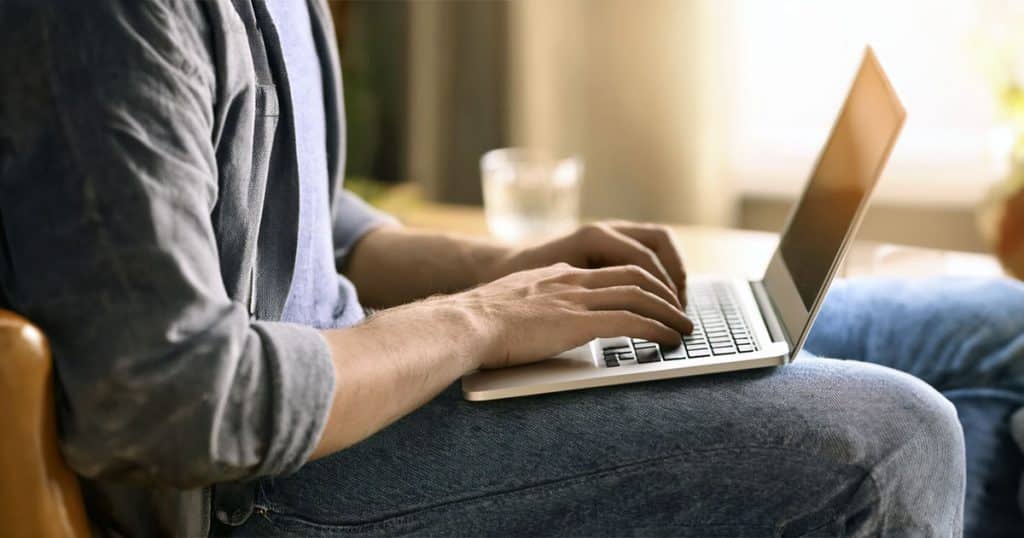 Closeup of young man typing on laptop