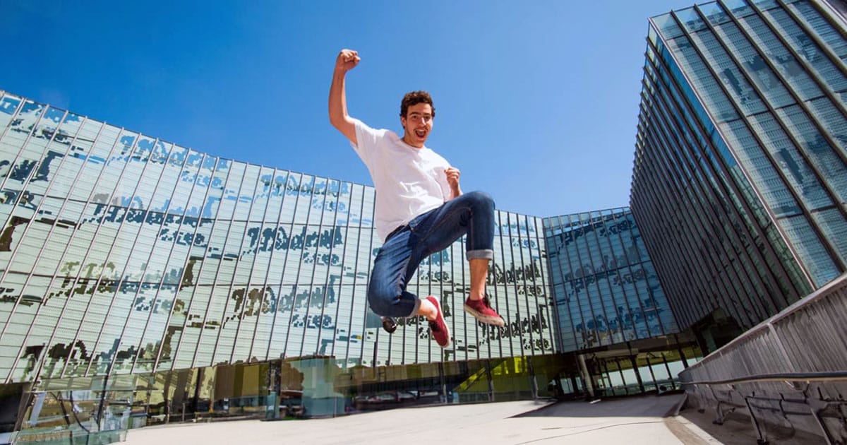 Male uni student leaping in triumph