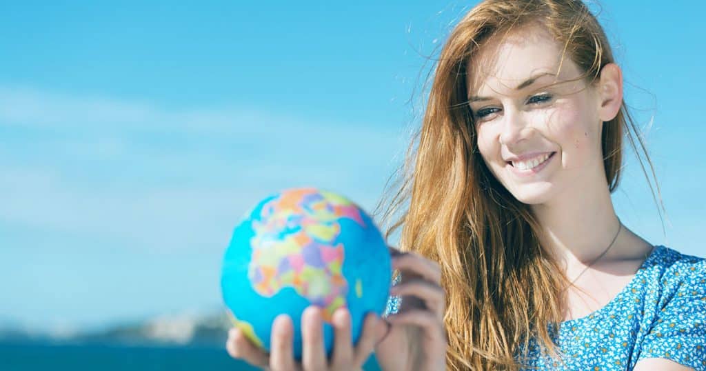 Woman smiling while holding world globe